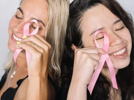 Two people smiling, holding awareness ribbons for a cause